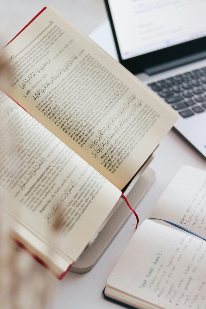 pexels photo 20593094 20593094 An open book and notebook on a desk with a laptop, capturing a study or work scene.